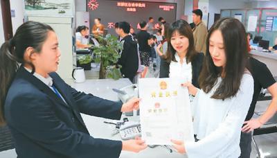 河北省承德市網(wǎng)絡代購經(jīng)營者陳晨(右)從工作人員手中接過帶有統(tǒng)一社會信用代碼的營業(yè)執(zhí)照。 劉環(huán)宇攝(人民圖片)