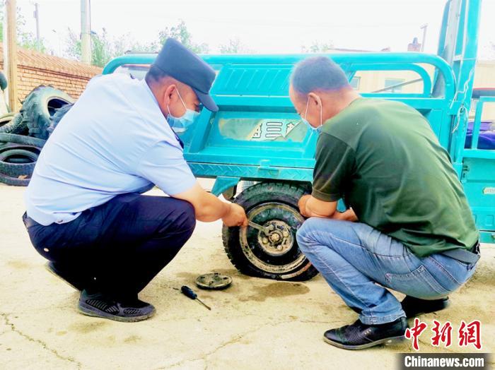 賽旦與民警共同維修三輪摩托車。　依力哈木江 攝