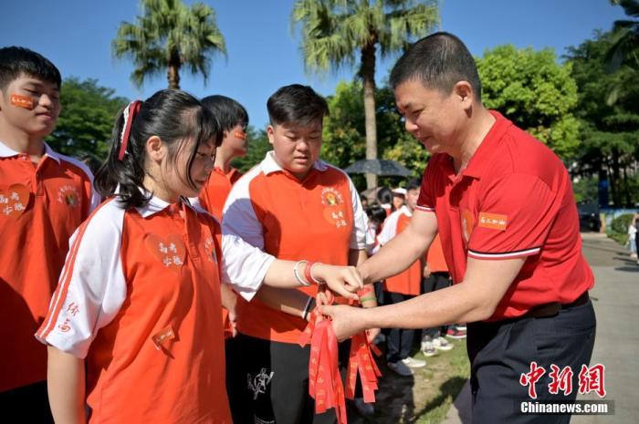 資料圖：廣西華僑實驗高中的教師為高三學子系上紅絲帶，盼望學子高考必勝。 俞靖 攝